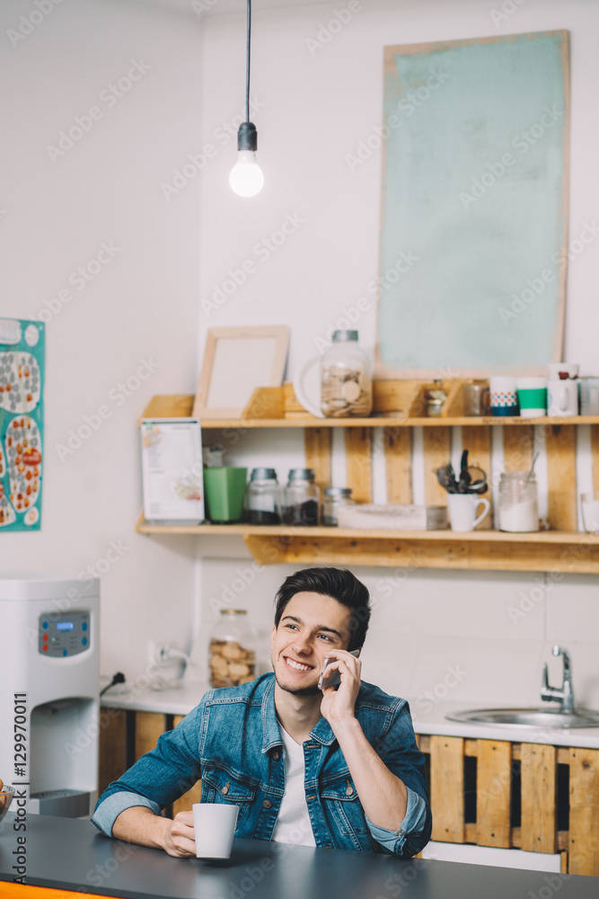 Young Man Relaxing Sitting In Kitchen Talking On Phone Young Man Relaxing Sitting In Kitchen Talking On Phone