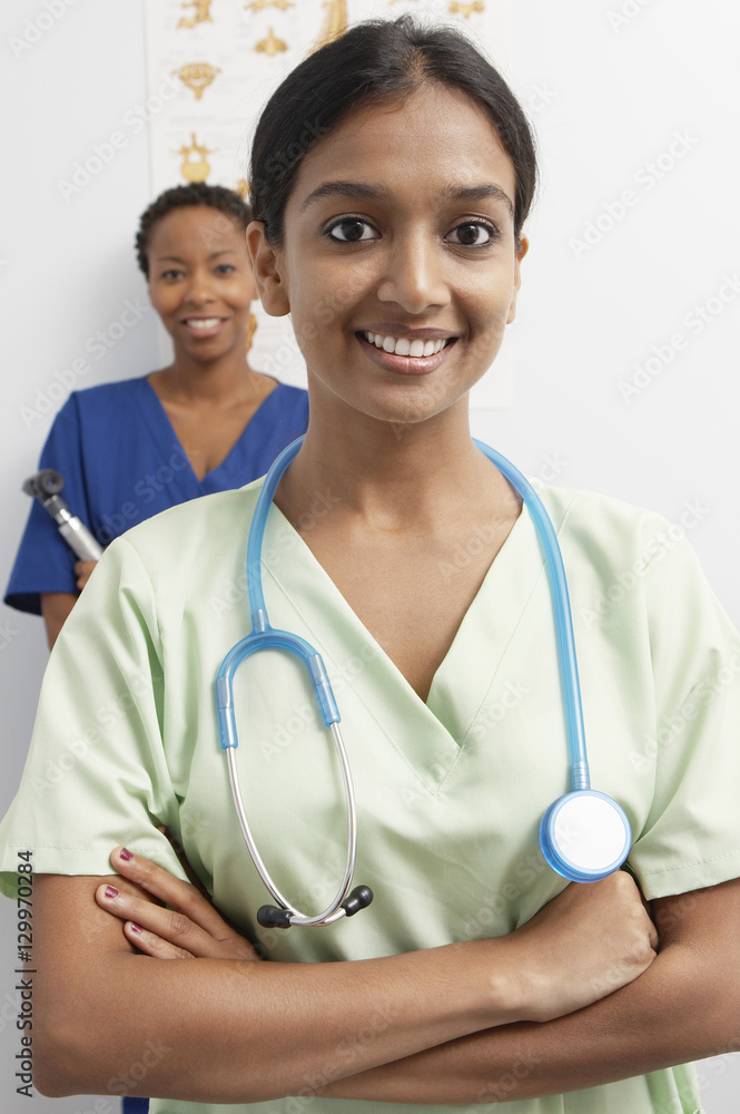 Happy female doctor wearing stethoscope around neck with nurse in the  background Stock Photo | Adobe Stock