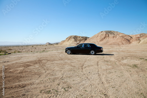 Rolls Royce car parked on unpaved road with tire tracks