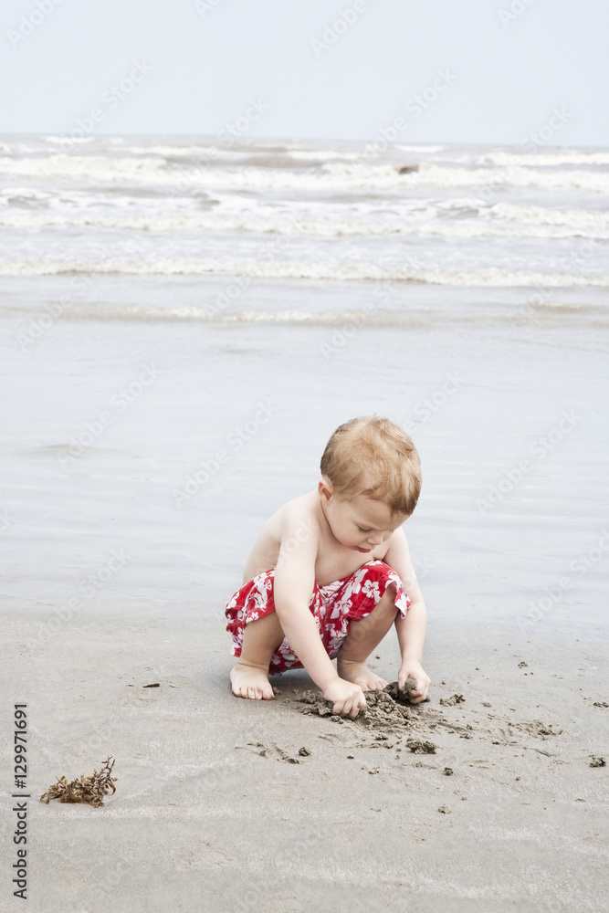 Full length of a little boy playing with sand on beach Full length of a little boy playing with sand on beach