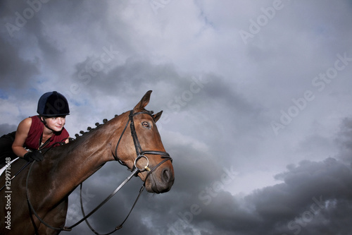 Low angle view of a female jockey riding on brown horse © moodboard