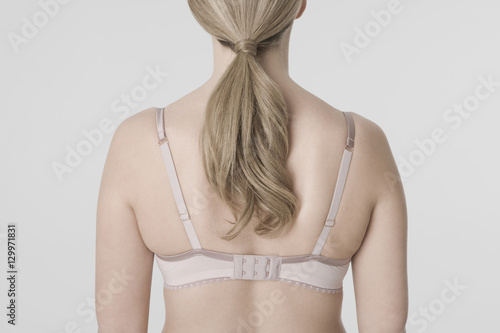 Closeup rear view of a blond woman wearing bra against gray background photo