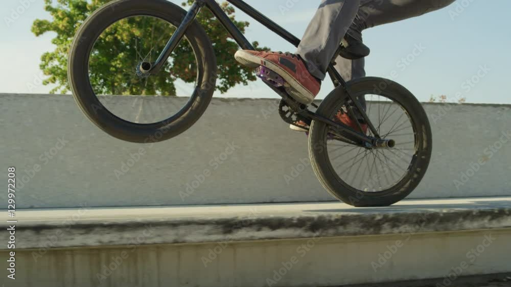 SLOW MOTION CLOSE UP: Extreme bmx biker jumping on bench and doing wheelie trick SLOW MOTION CLOSE UP: Extreme bmx biker jumping on bench and doing wheelie trick