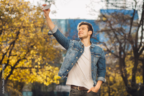 Young man standing outdoors holding mobile phone