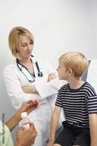 Female doctor looking at boy while nurse holding syrup cup in the clinic