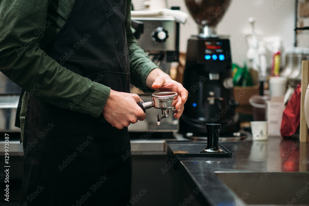  Man in black apron prepares the coffee machine