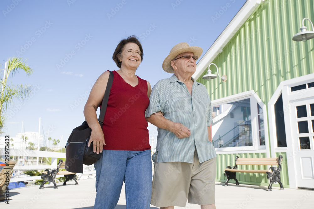 Happy senior Caucasian couple walking together on town square