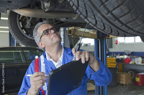 Mechanic analyzing car engine at auto repair shop © moodboard