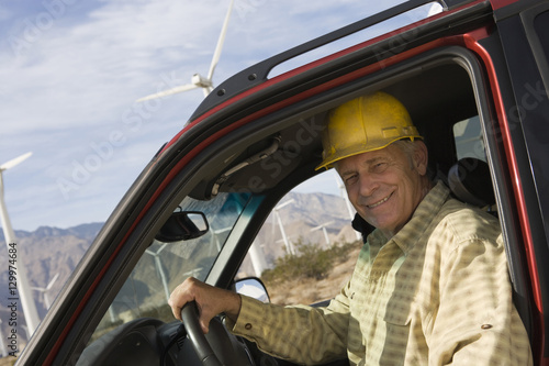 Portrait of happy senior male worker sitting in pickup truck at windfarm © moodboard
