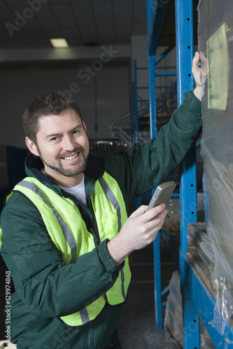 Portrait of a smiling man using calculator in the factory