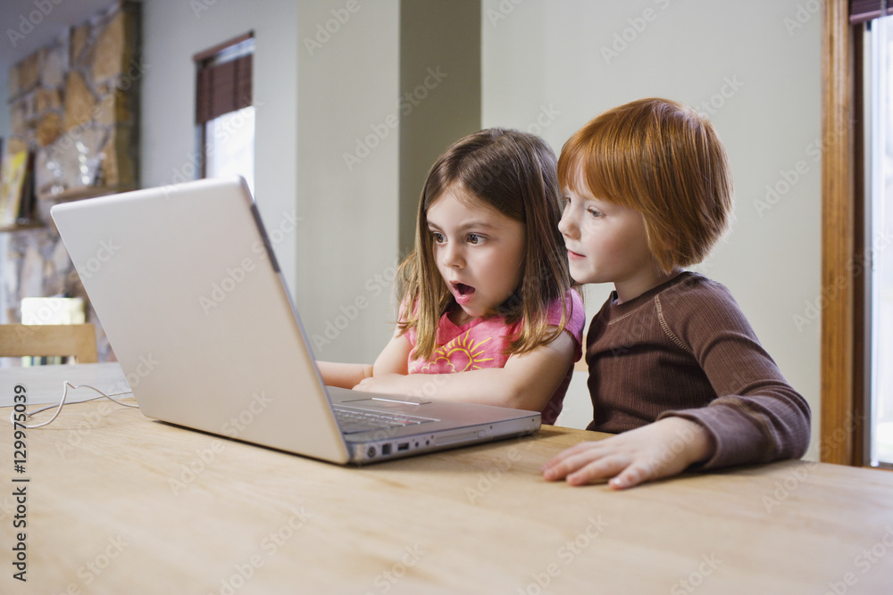 Shocked young girls using laptop at table Shocked young girls using laptop at table