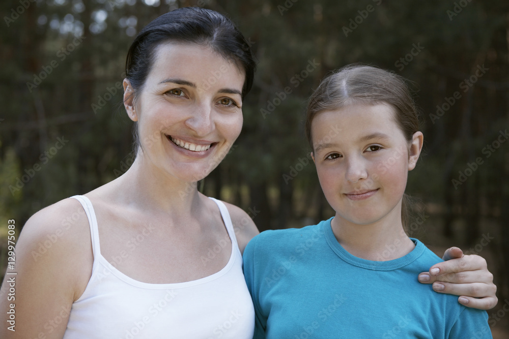 Closeup portrait of a mother and daughter against blurred plants Closeup portrait of a mother and daughter against blurred plants