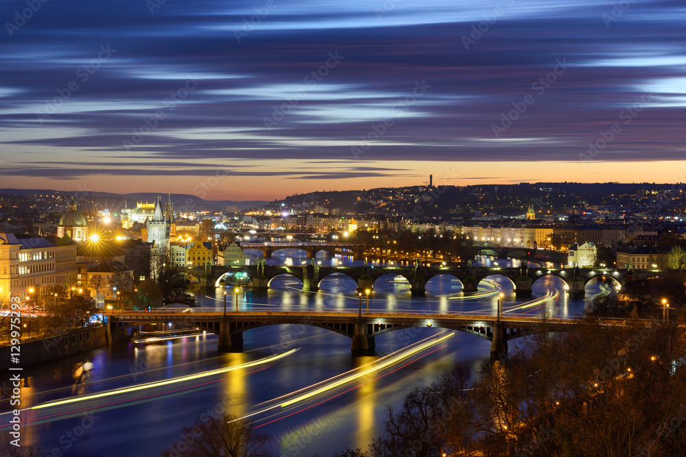 River traffic near majestic Charles Bridge during sunset with several boats, Prague, Czech republic