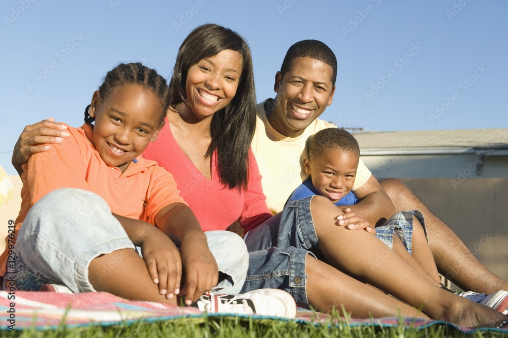 Portrait of a happy African American family sitting together in lawn on a sunny day Portrait of a happy African American family sitting together in lawn on a sunny day