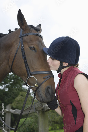 Side view of a young woman kissing a horse outdoors