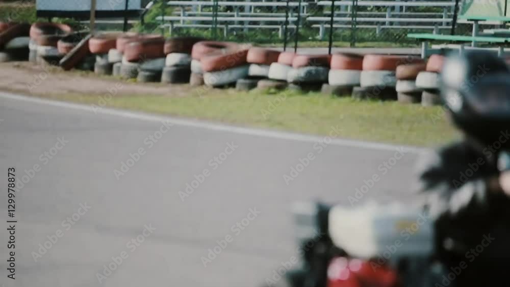 Kart drivers moving on a go kart track passing by the camera. Kart drivers moving on a go kart track passing by the camera.