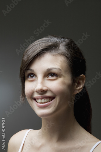 Closeup of a happy young woman looking up against gray background