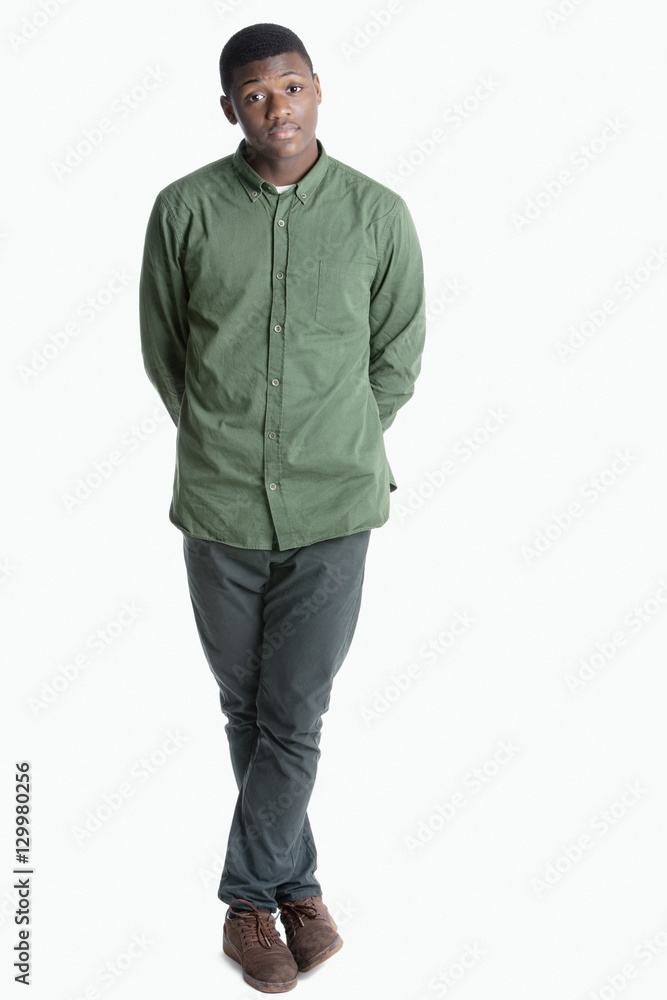 Portrait of a young African American man standing with legs crossed over gray background Portrait of a young African American man standing with legs crossed over gray background