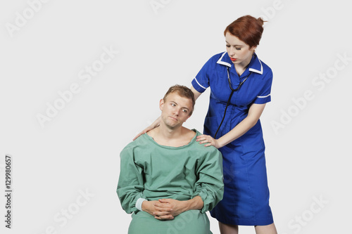 Female nurse consoling male patient against gray background