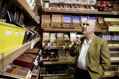 Фотография Small tobacco store owner looking at cigar boxes on display in shop