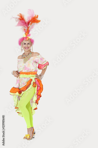 Portrait of happy senior woman in Brazilian outfit against gray background