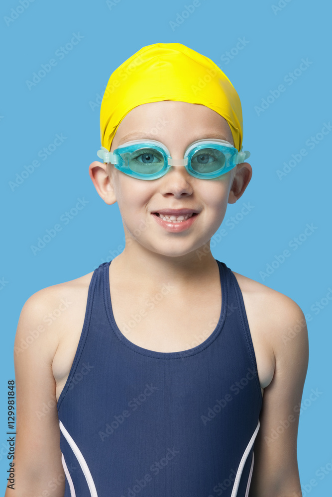 portrait of a happy young girl wearing swim goggles over blue background portrait of a happy young girl wearing swim goggles over blue background