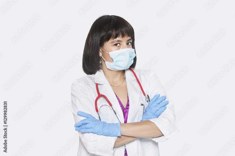 Portrait of female veterinarian standing arms crossed over gray background Portrait of female veterinarian standing arms crossed over gray background