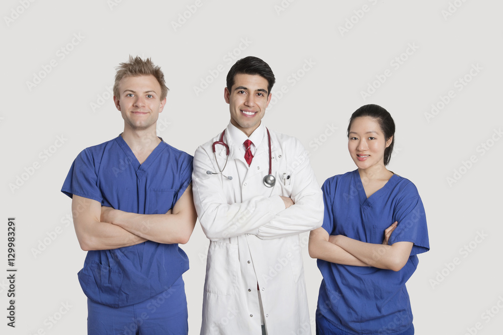 Portrait of multi ethnic healthcare professionals standing with arms crossed over gray background Portrait of multi ethnic healthcare professionals standing with arms crossed over gray background