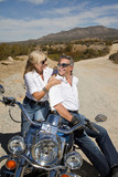 Senior couple sitting on motorcycle and smiling at each other