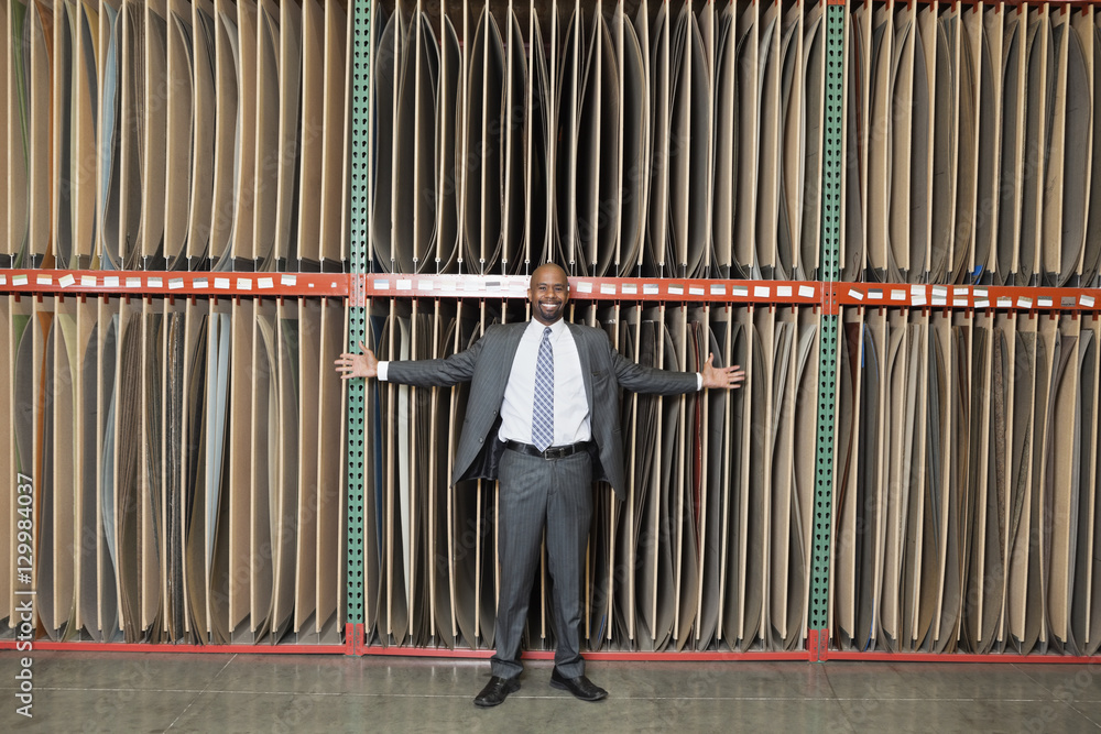 Portrait of happy African American businessman standing arms outstretched in front of thin veneer sheets