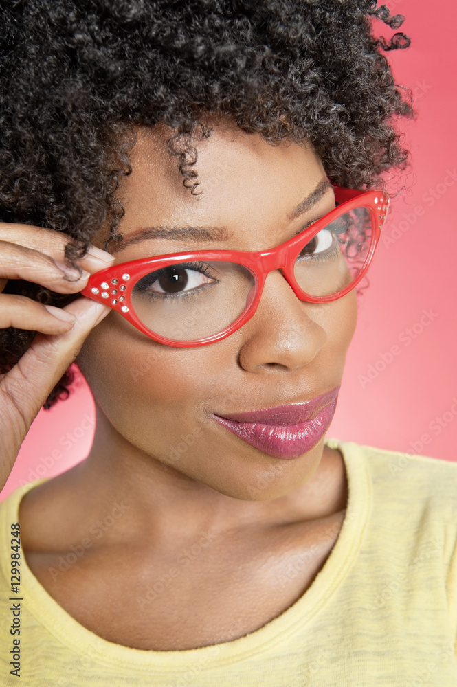 Portrait of an African American woman wearing retro glasses over colored background Portrait of an African American woman wearing retro glasses over colored background