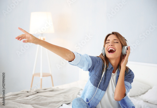 Beautiful young woman listening to music in headphones at home