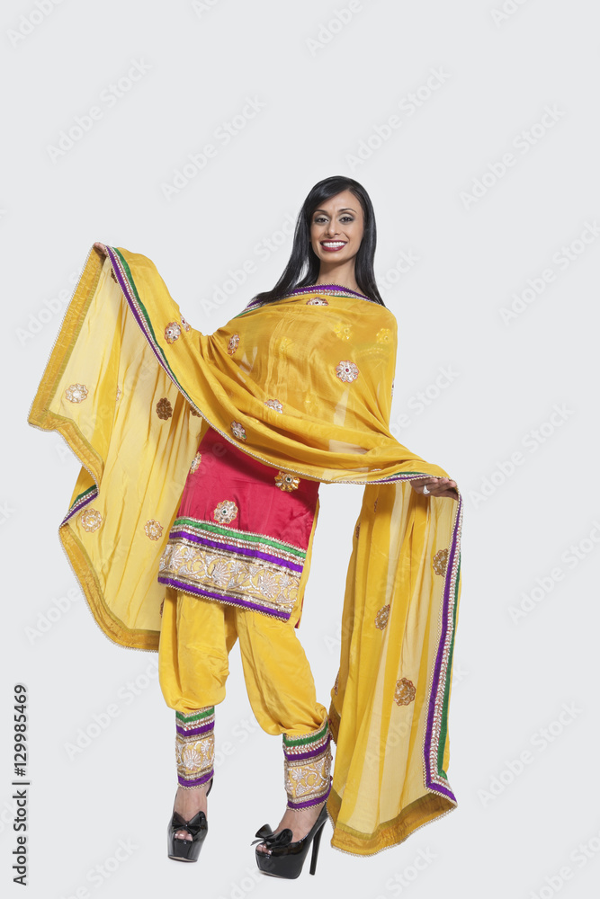 Full length of an Indian woman in salwar kameez standing over gray background