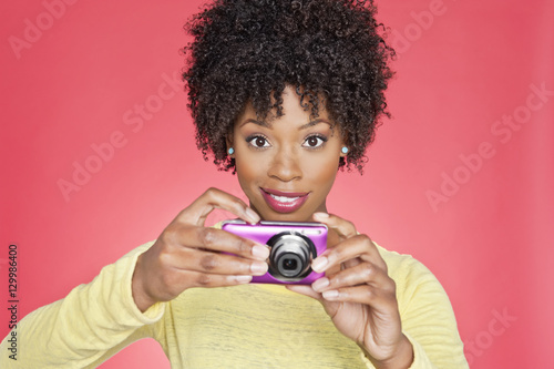 Portrait of an African American woman holding a camera over colored background © moodboard