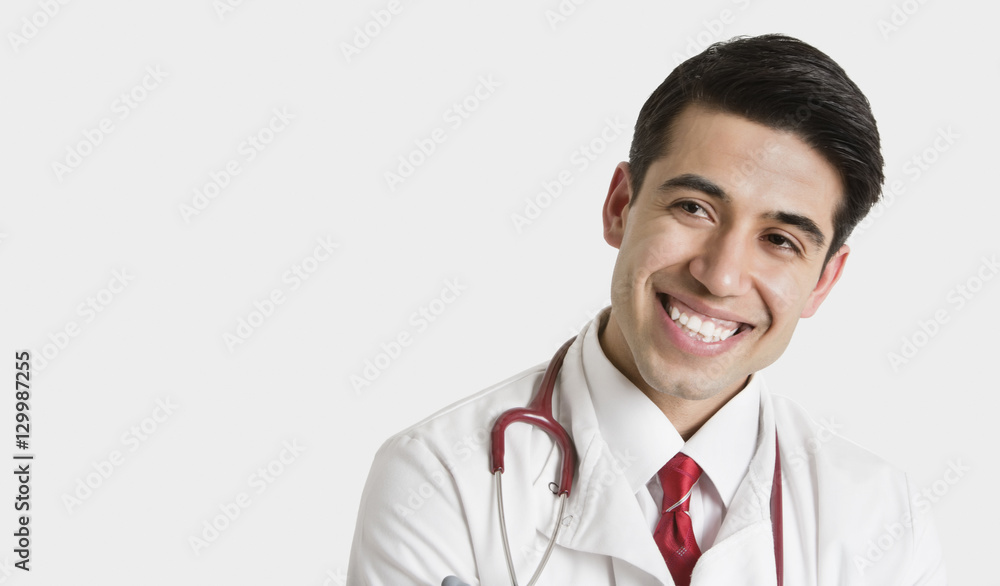 Cheerful Indian male doctor looking sideways over light gray background Cheerful Indian male doctor looking sideways over light gray background