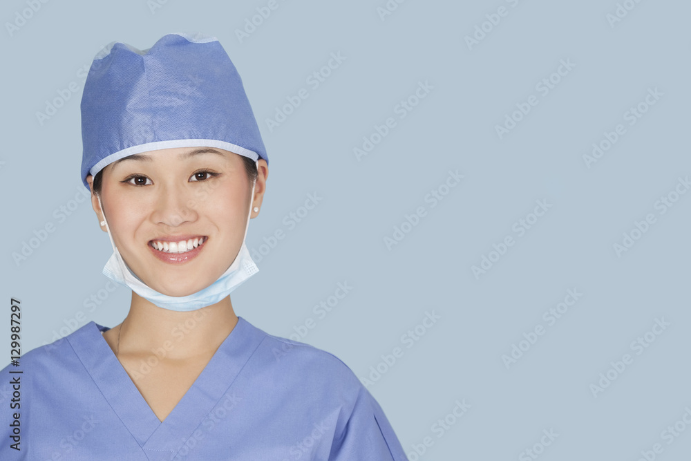 Close-up portrait of female surgeon smiling over light blue background Close-up portrait of female surgeon smiling over light blue background