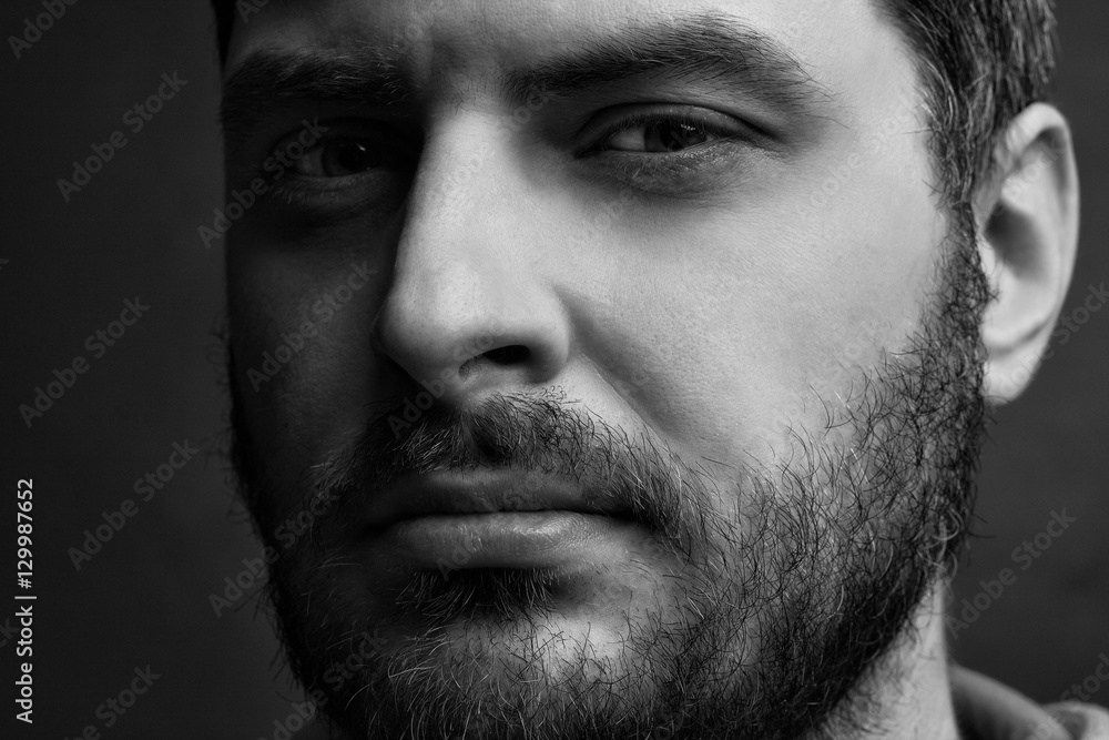 Low key black and white portrait of a serious thinking man with a thick beard Low key black and white portrait of a serious thinking man with a thick beard