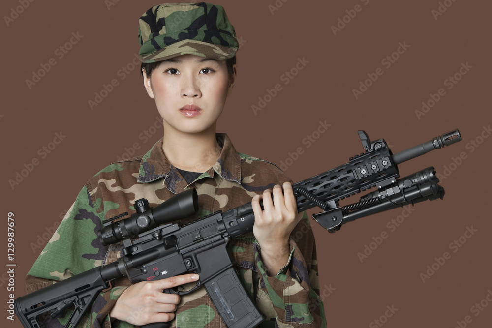Portrait of beautiful young US Marine Corps soldier with M4 assault rifle over brown background Portrait of beautiful young US Marine Corps soldier with M4 assault rifle over brown background