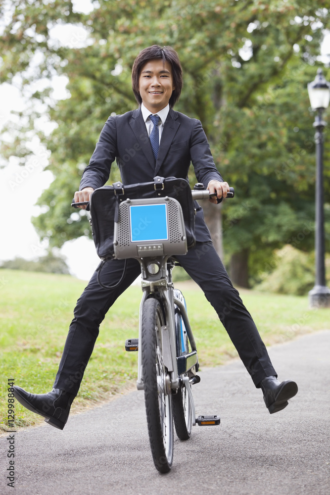 Portrait of young businessman riding bicycle with apart