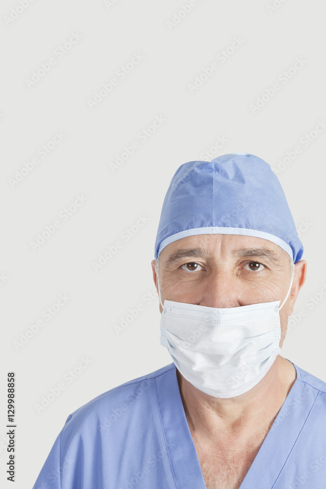 Portrait of senior surgeon with surgical cap and mask over gray background Portrait of senior surgeon with surgical cap and mask over gray background