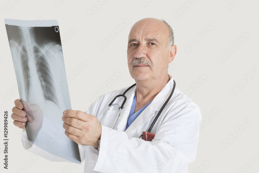 Portrait of senior doctor holding medical radiograph over gray background Portrait of senior doctor holding medical radiograph over gray background