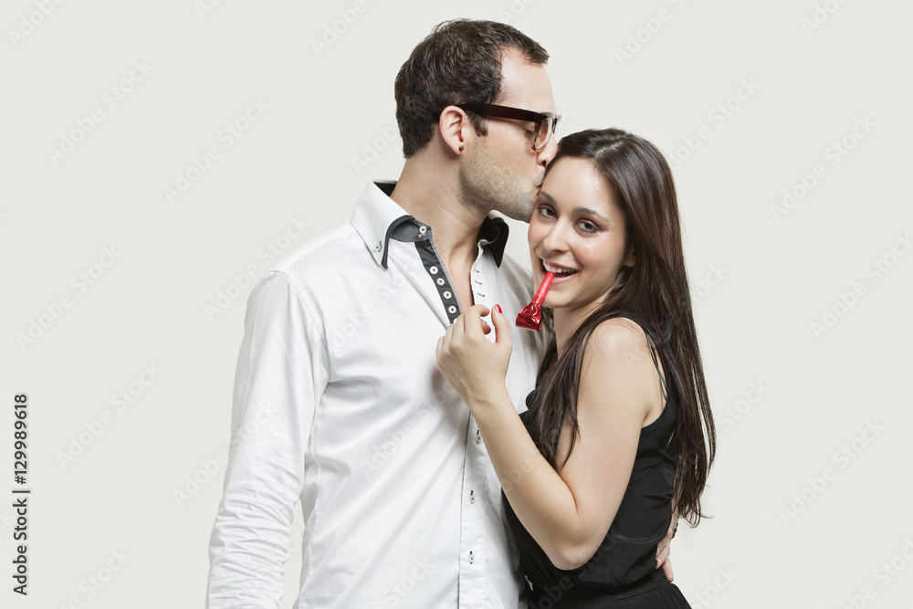 Young couple with party puffer against gray background Young couple with party puffer against gray background