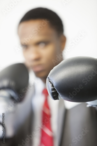 Businessman wearing boxing gloves with focus on gloves © moodboard