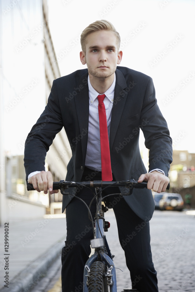 Young businessman riding bicycle on street Young businessman riding bicycle on street