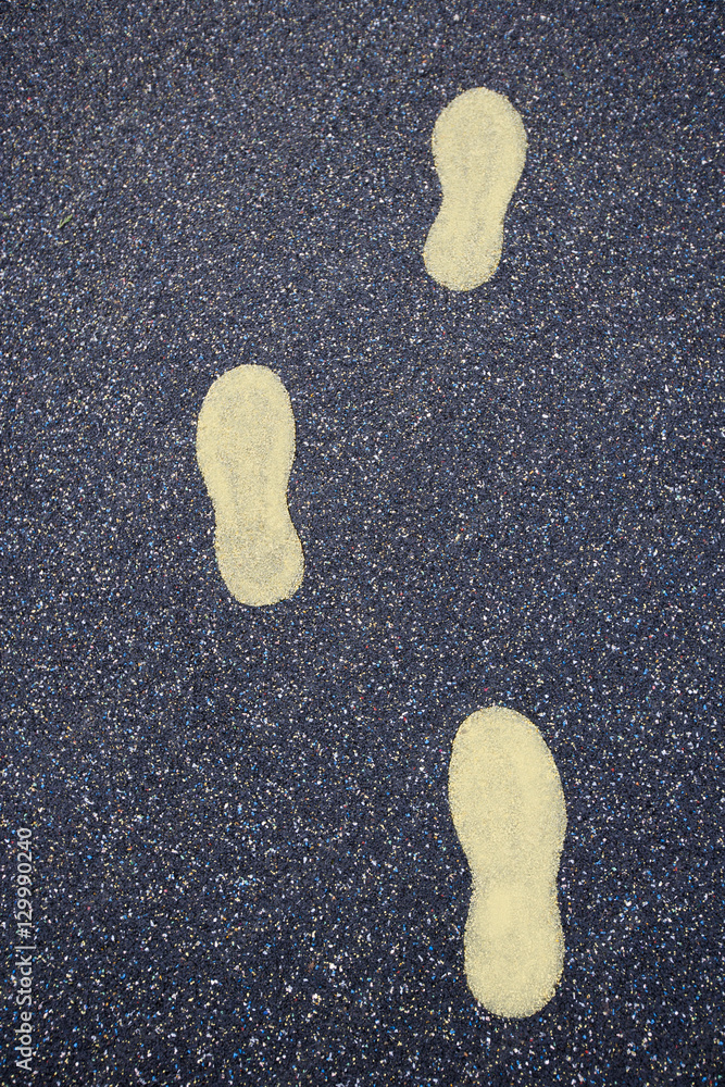 Yellow footsteps drawn in playground rubber flooring Yellow footsteps drawn in playground rubber flooring