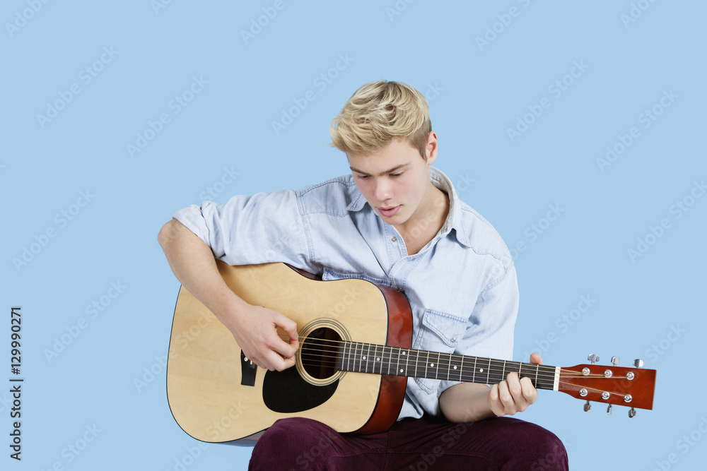 Young man playing guitar over blue background