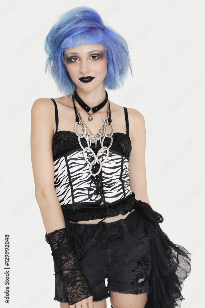 Portrait of young female punk with dyed hair over gray background