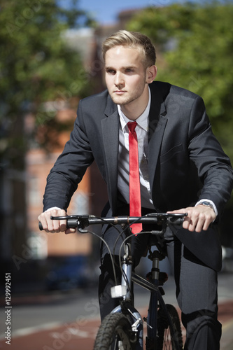 Young businessman riding bicycle on street