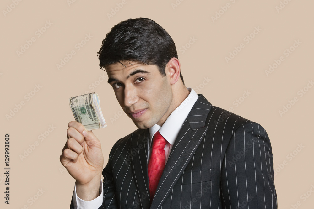Portrait of a young businessman showing paper money over colored background Portrait of a young businessman showing paper money over colored background