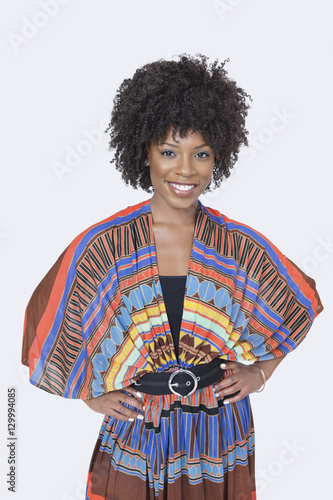Portrait of beautiful African American woman in traditional wear standing over gray background